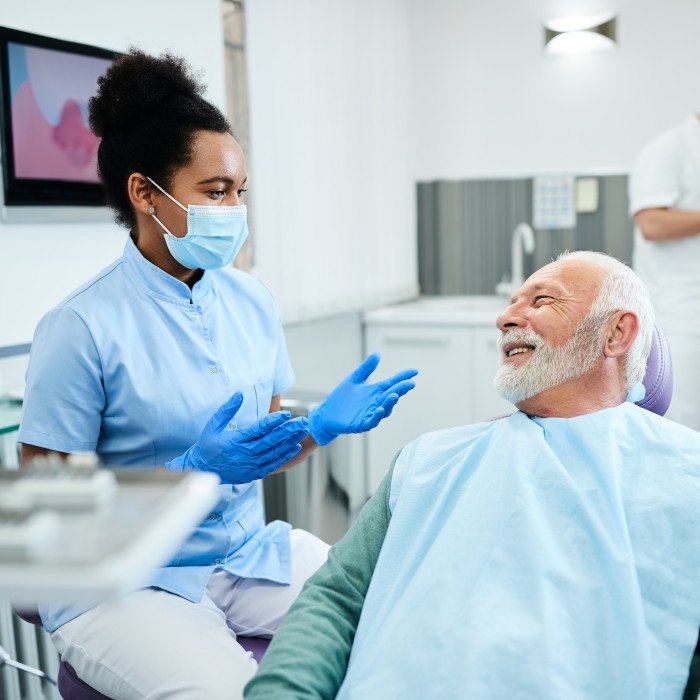 Dentist smiling while talking to patient in treatment chair