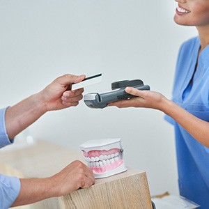 A dental patient paying their dentist for dental implants