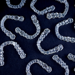 Bird’s eye view of a bunch of clear aligners arranged over a black background