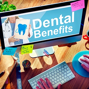 A cluttered desk with a computer with “Dental Benefits” on the screen