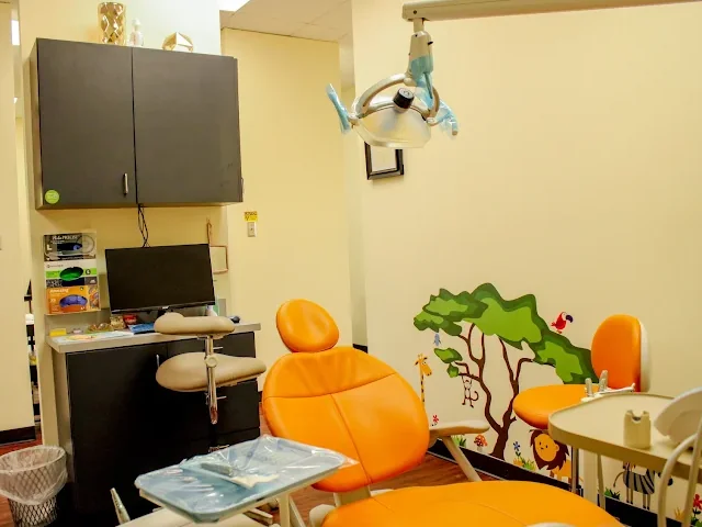 Treatment room at Sonria Dentista Commerce with an orange dental chair and a jungle mural for kids