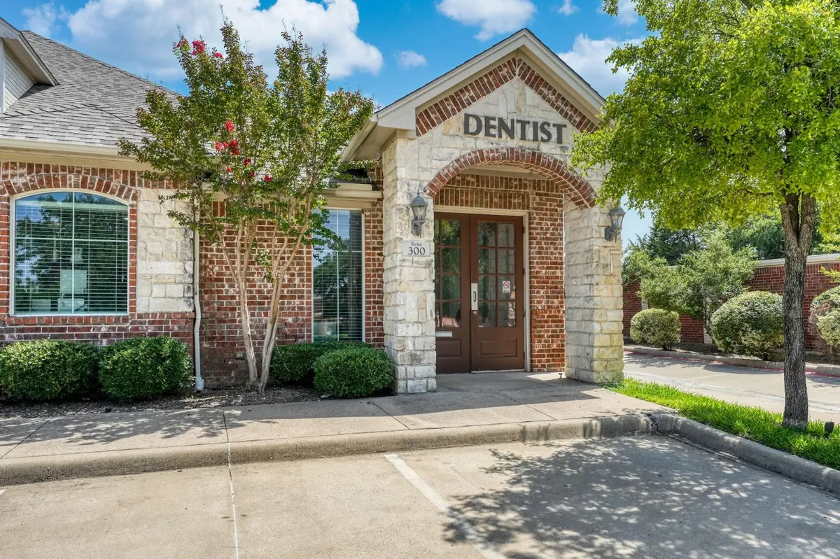 Entrada de la Suite 300 de Sonria Dentista Grand Prairie, un arco de ladrillo y piedra bajo el letrero Dentist